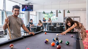Une table de billard dans un intérieur moderne, avec un téléviseur fixé au mur juste au-dessus.