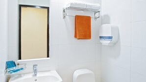 A bathroom with a white sink, a toilet, a mirror, and a towel rack. - Hotel 81 Fuji (Singapore)
