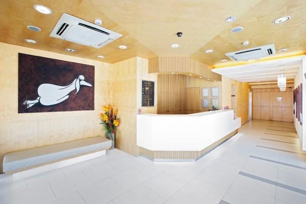 A modern reception area with a white reception desk, a large abstract painting, and a bench.