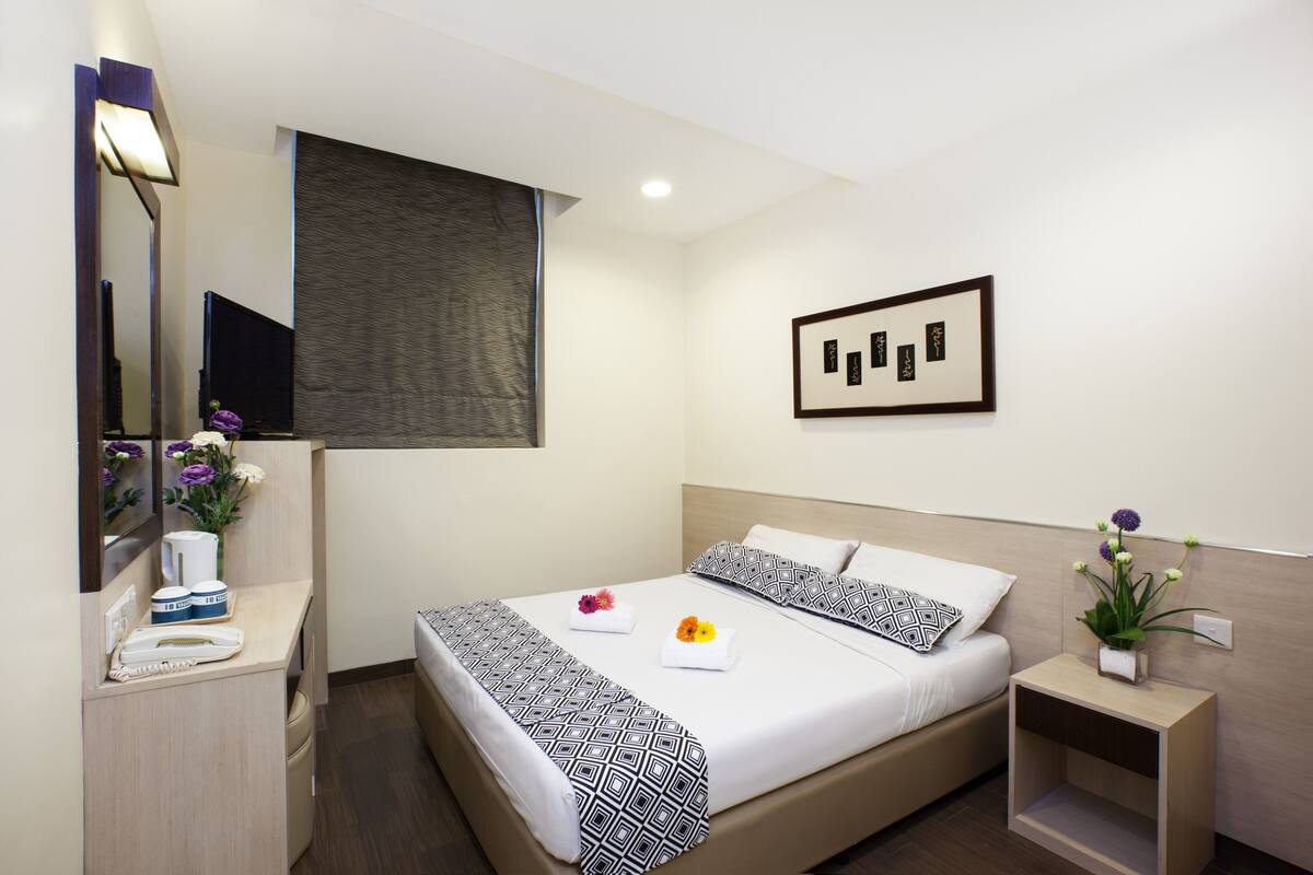 A modern hotel room with a bed, bedside table, and a mirror.