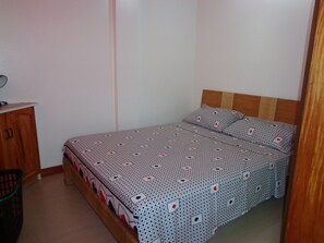 Un dormitorio con una cama, cabecera de madera y un pequeño aparador de madera.