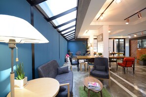 Un interior moderno con una pared azul de acento, un tragaluz, una zona de comedor y una recepción.