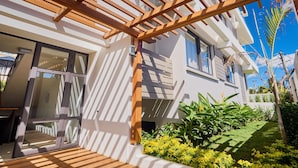 Ein modernes Haus mit einer Holzpergola, großen Fenstern und einem gepflegten Garten.