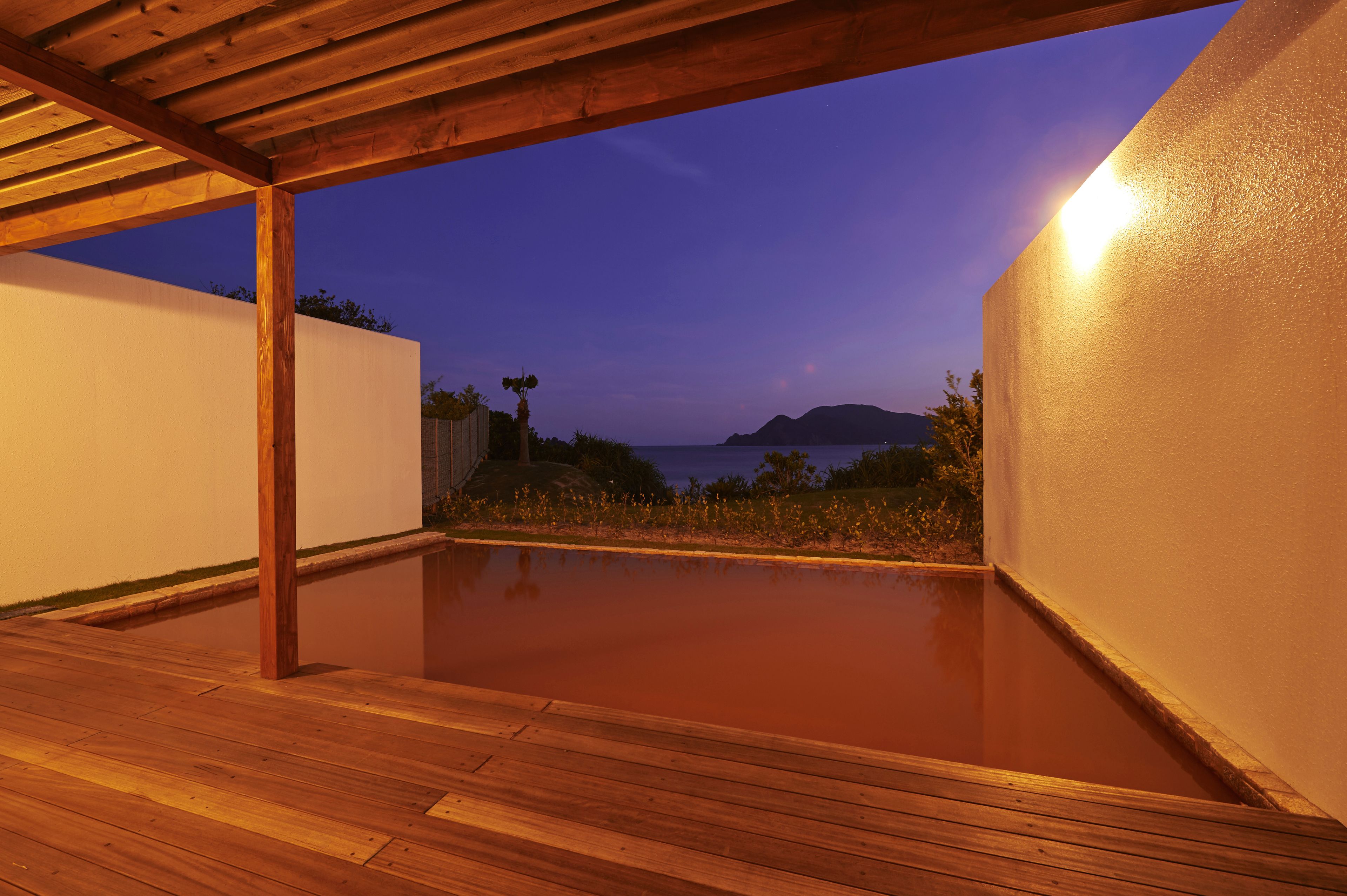 A wooden deck with a view of the sea at dusk.