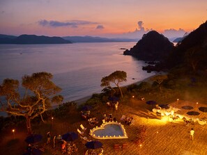 A beachside resort with a pool, outdoor seating, and a view of the sea and mountains. - THE SCENE amami spa & resort (Setouchi)