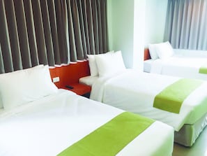 Habitación de hotel con dos camas, una mesita de noche de madera y un control remoto.