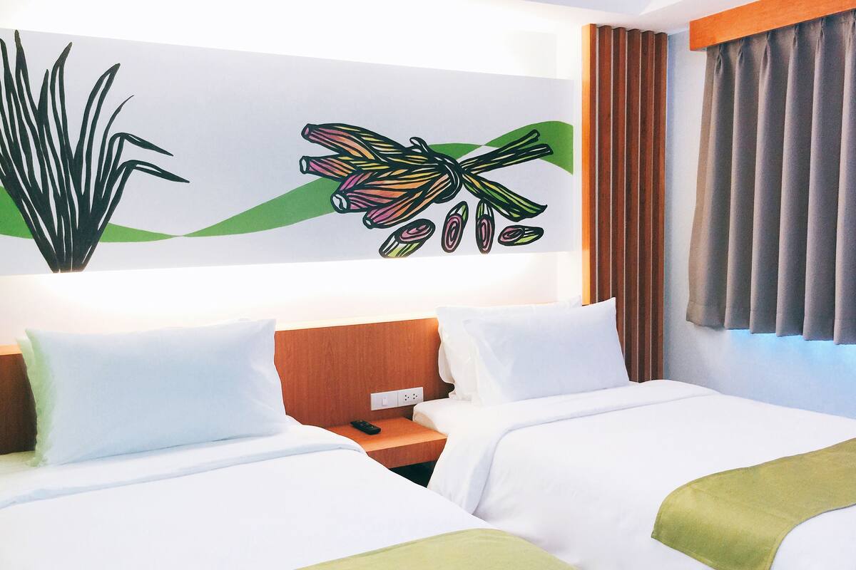 A hotel room with two beds, a nightstand, a wall art piece, and a window with curtains.