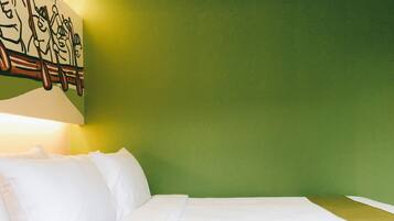 Una habitación de hotel con una cama, ropa de cama blanca y una pared verde.