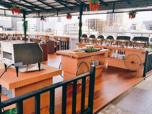 Een restaurant met terras, een etalage met eten en uitzicht op de skyline.