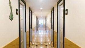 A long, narrow hotel corridor with doors on both sides, leading to rooms.