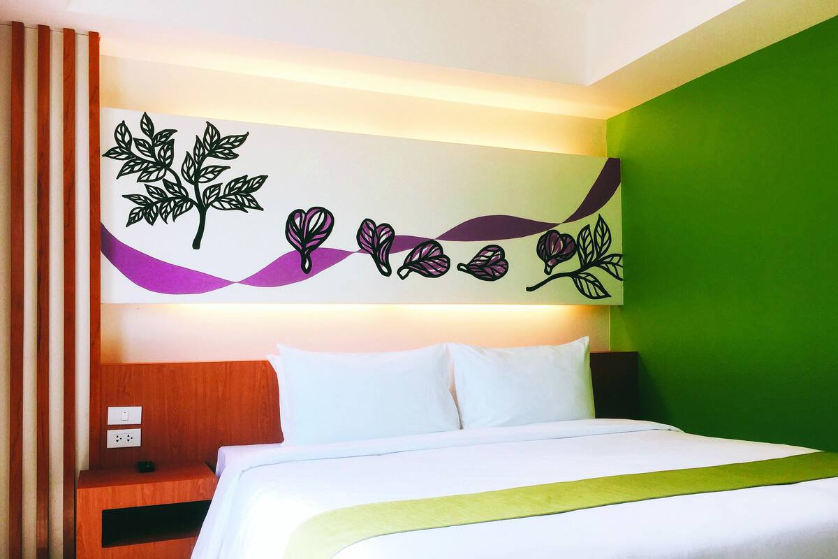 A hotel room with a bed, a nightstand, and a wall decoration.