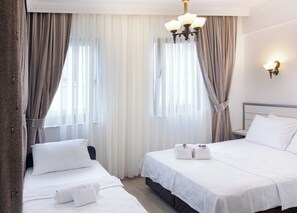 Ein Hotelzimmer mit zwei Betten, weißen Bettwäsche, einem Chandelier und Vorhängen.