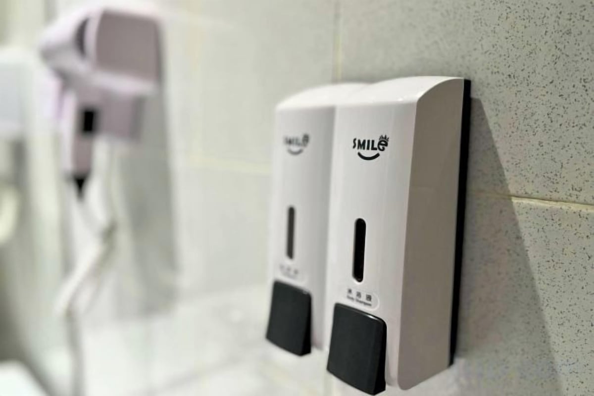 A wall-mounted soap dispenser with a smiley face design.