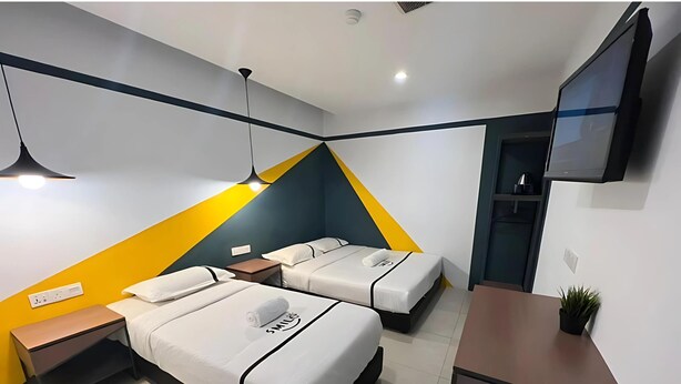 A modern hotel room with two beds, a desk, a TV, and a small plant. - Smile Hotel Cheras Sri Permaisuri (Kuala Lumpur)