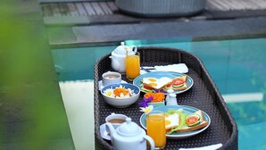 A breakfast tray with eggs, toast, and juice on a glass table near a pool. - Akasa Villa Tulamben (Tulamben)