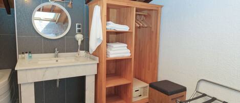 A modern bathroom with a wooden vanity, a round mirror, and a built-in shelf for towels.
