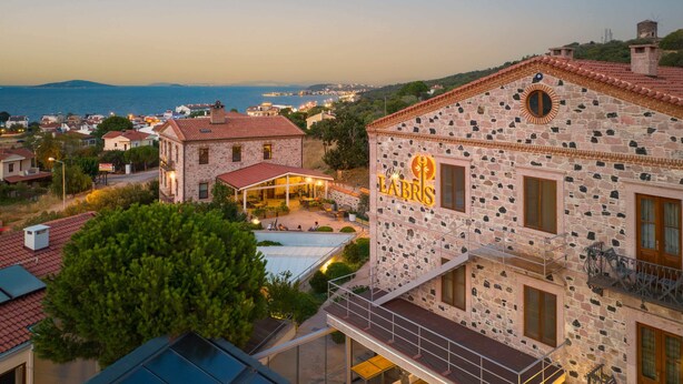 A stone building with a sign reading "Oral LABS" and a pool area. - Cunda Labris Hotel (Ayvalik)