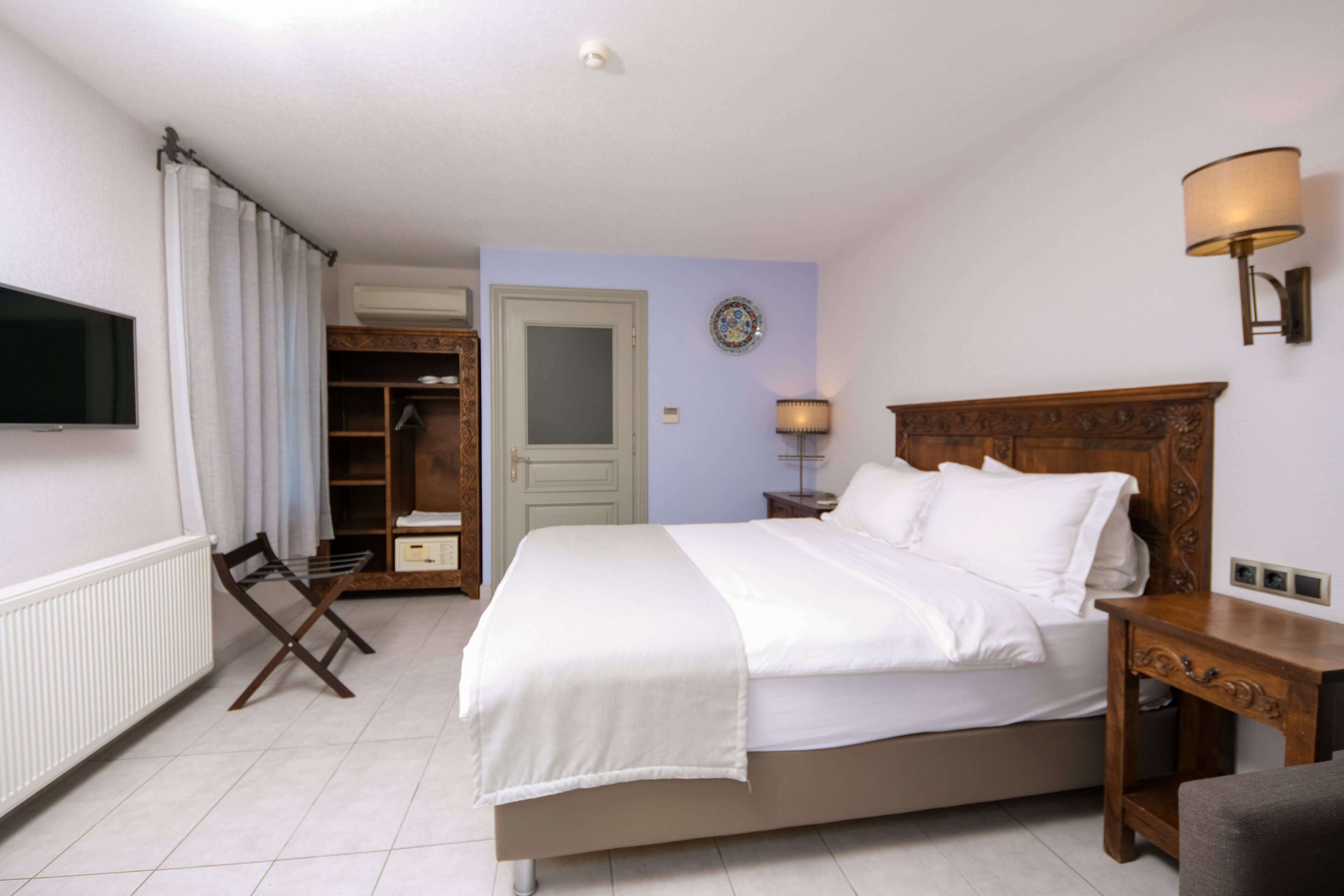 A bedroom with a bed, a TV, a wardrobe, a bedside table, and a lamp.