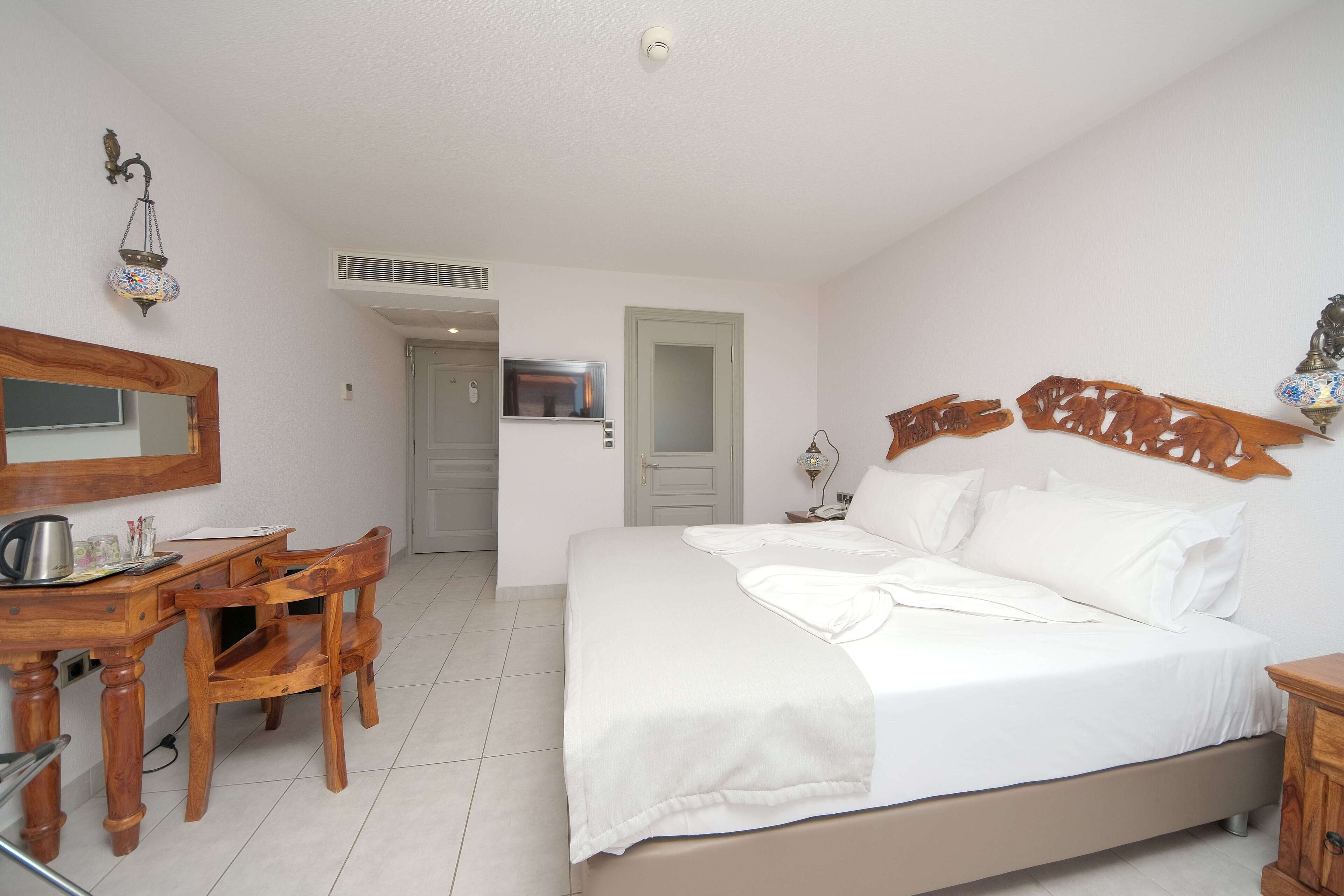 Un dormitorio con cama, escritorio de madera, silla y espejo.