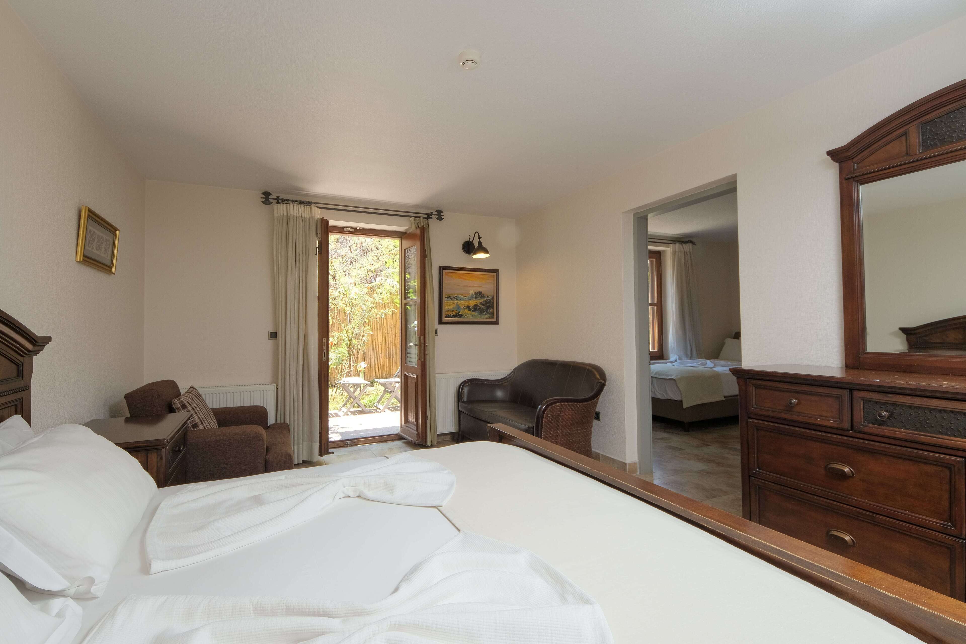 Um quarto com uma cama grande, uma cômoda de madeira, uma cadeira e um quadro na parede.