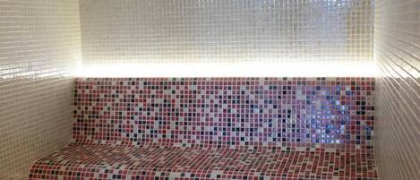 Une pièce avec un banc et un mur recouvert de mosaïques.
