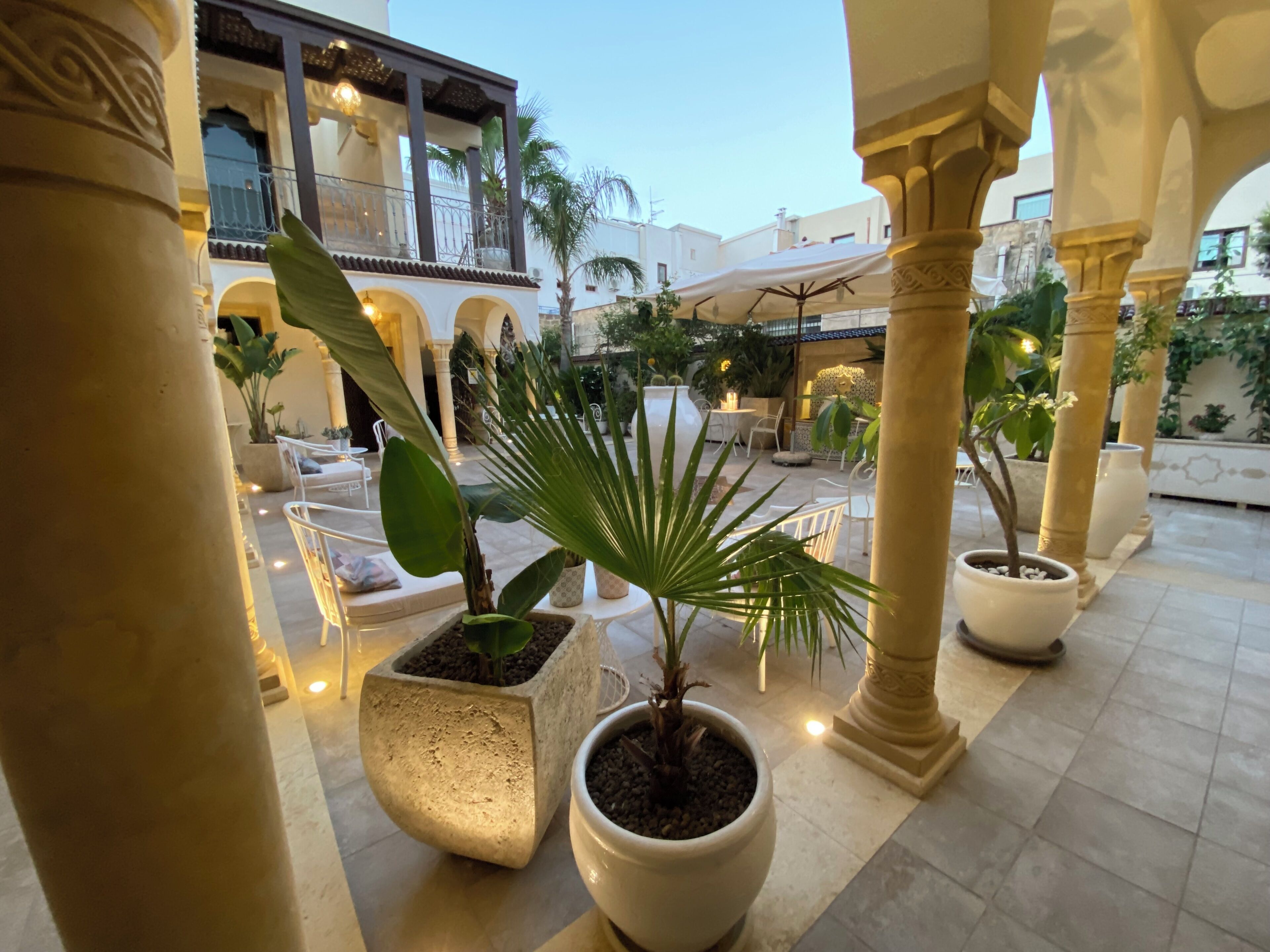 A courtyard with potted plants, seating areas, and a building with balconies.