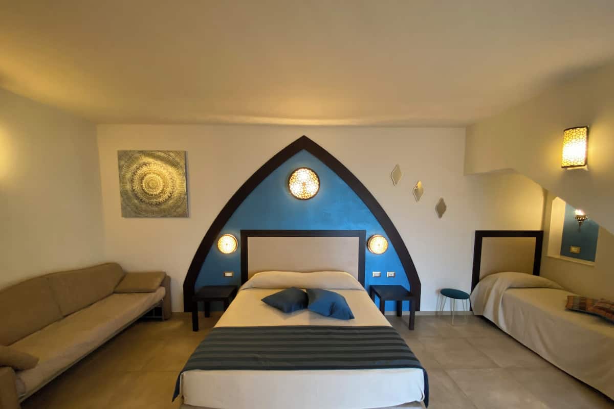 A bedroom with a large bed, a sofa, and a unique arched ceiling design.