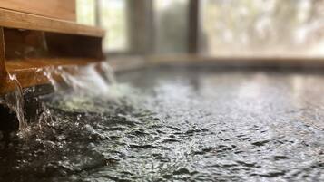 Primer plano de agua fluyendo desde una estructura de madera hacia una superficie húmeda.