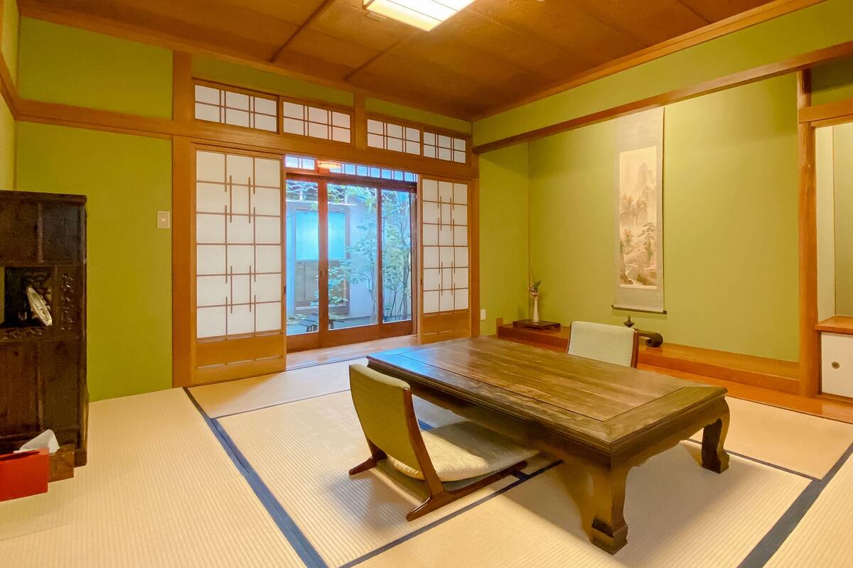 A traditional Japanese room with tatami flooring, a low wooden table, and sliding doors.
