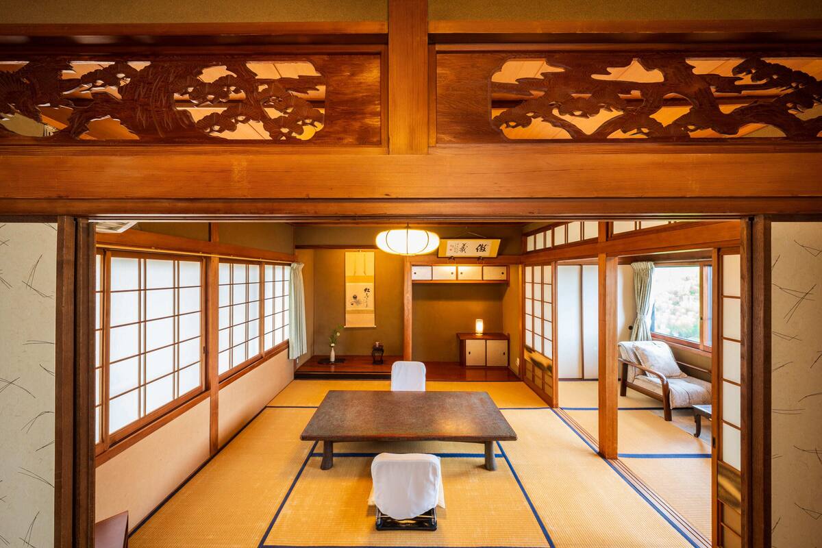A traditional Japanese room with tatami flooring, a low table, and sliding doors.