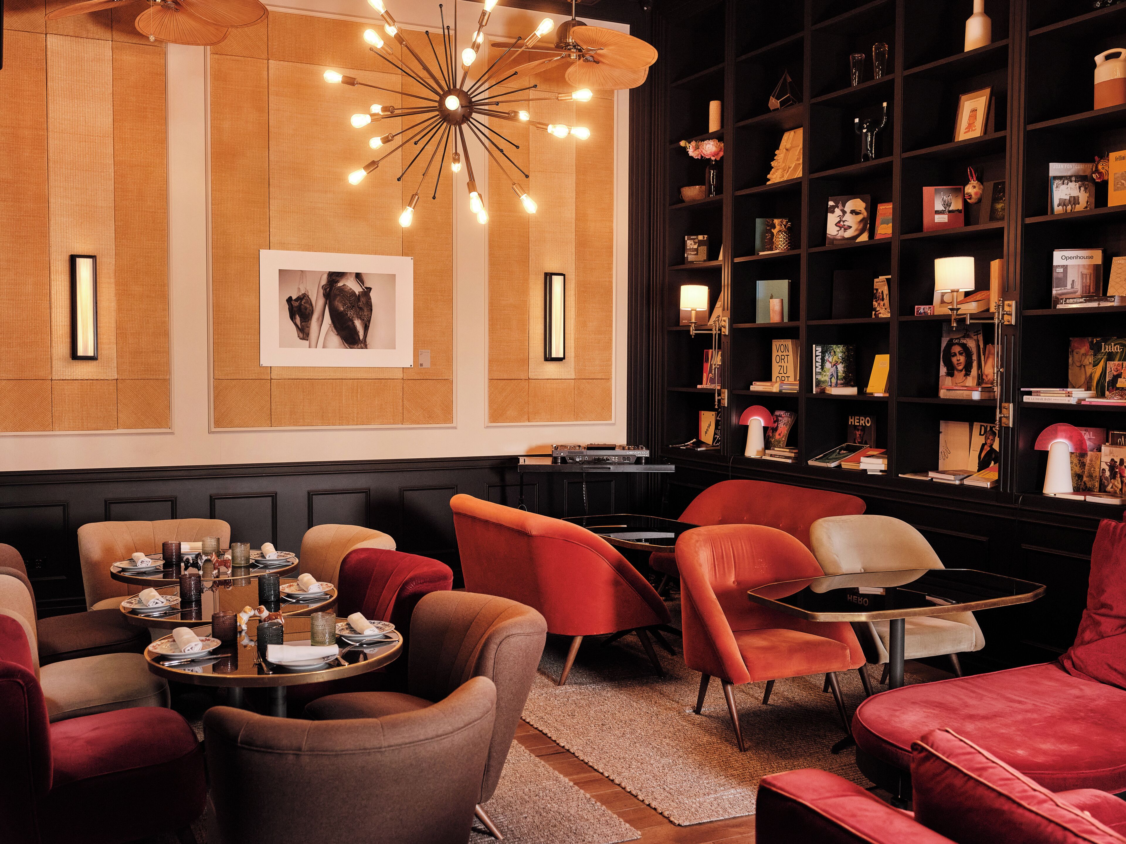 A modern interior with a central seating area, a bookshelf, and a unique ceiling light fixture.