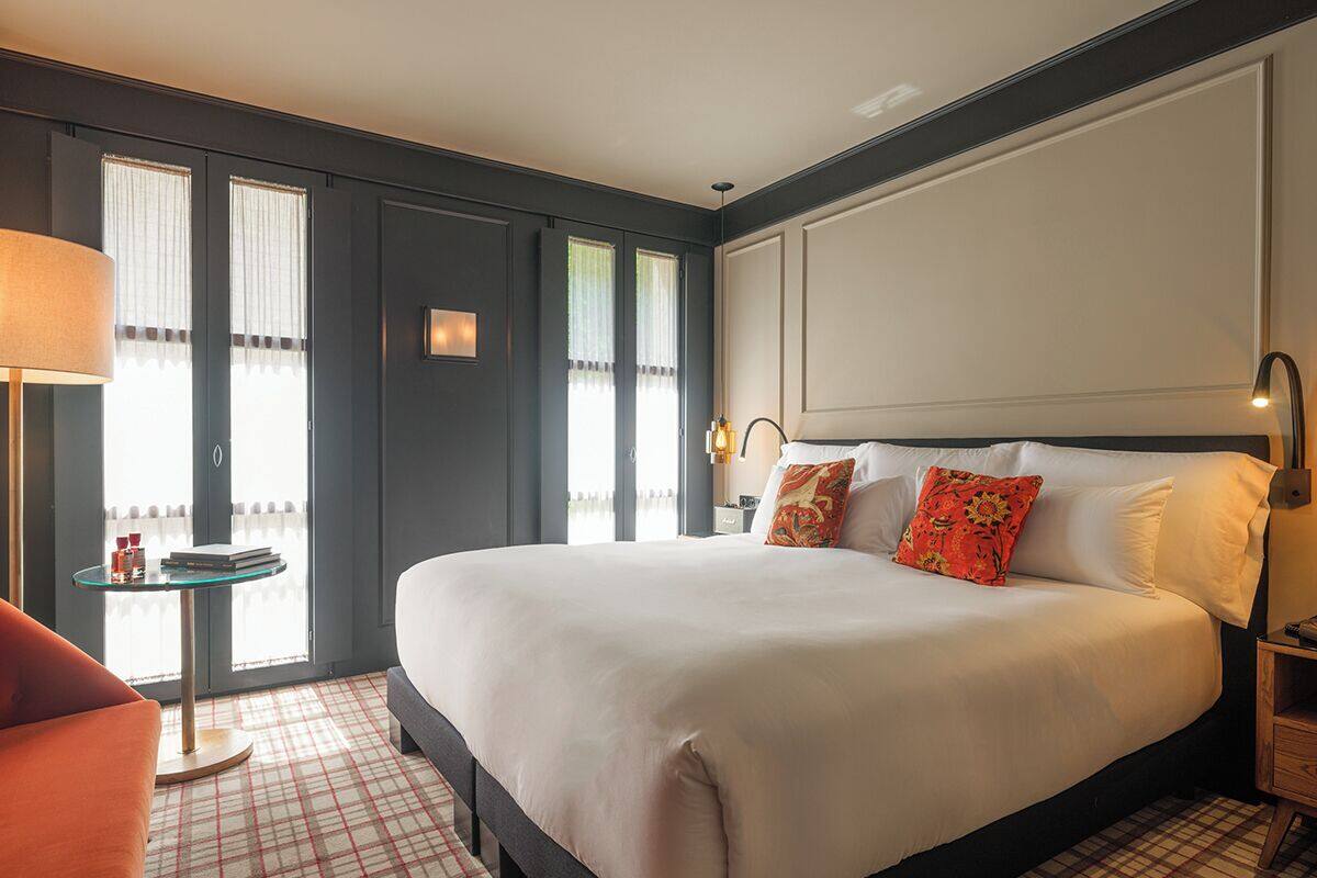 A hotel room with a large bed, a round table, and a chair.