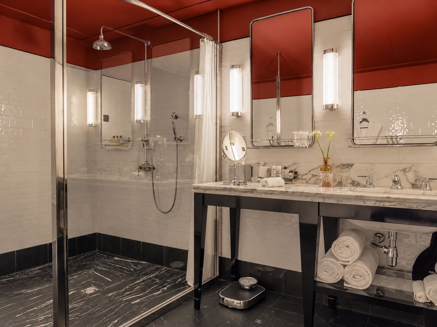A modern bathroom with a glass shower enclosure, a marble countertop, and a scale.