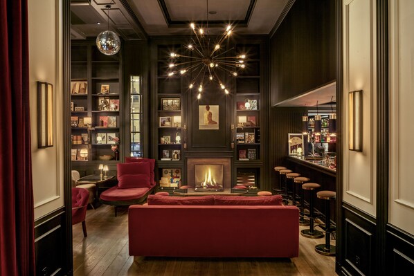 A cozy lounge area with a fireplace, red seating, and a bar with stools. - WITTMORE HOTEL - Adults Only (Barcelona)