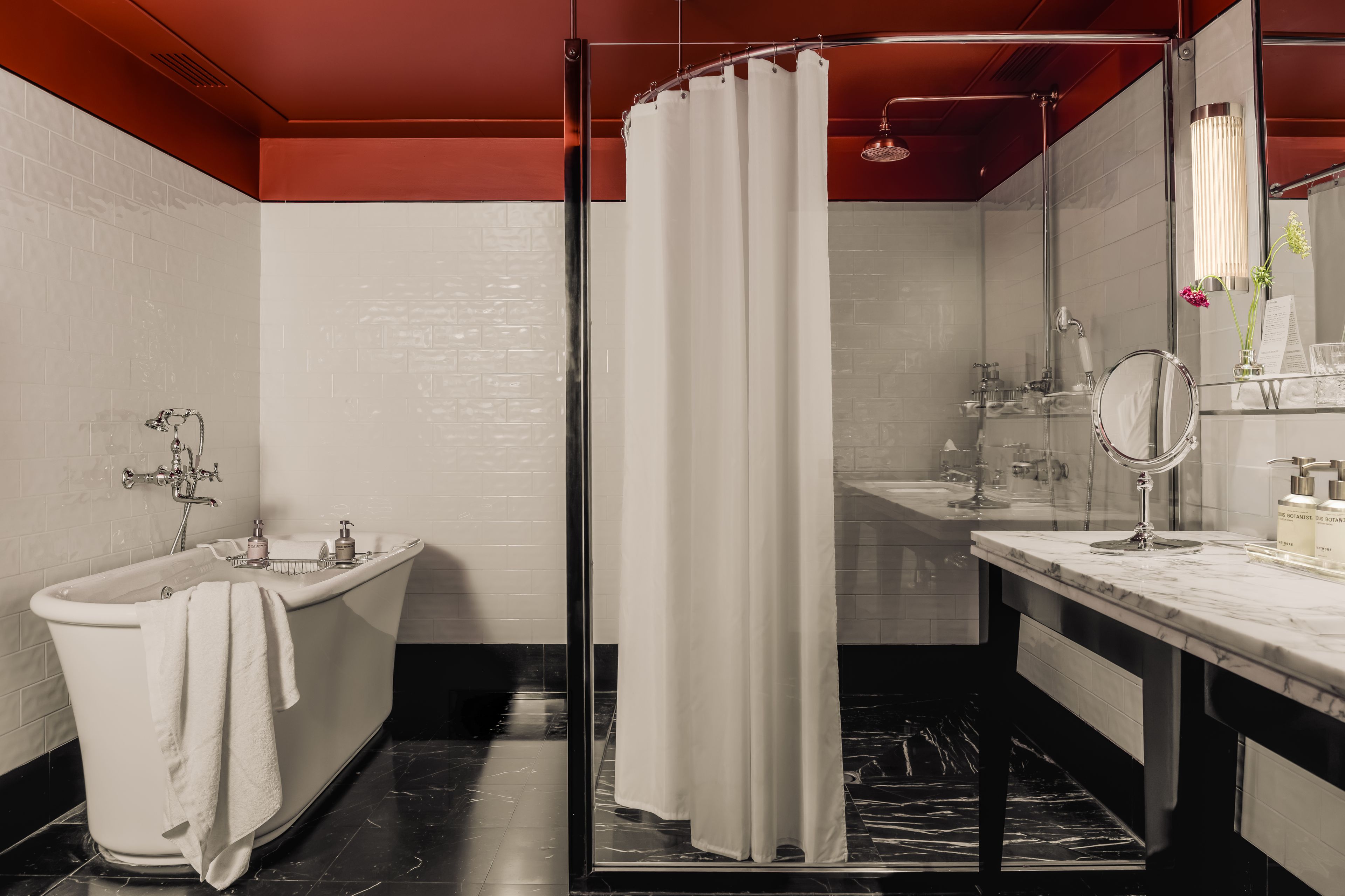 Ein modernes Badezimmer mit einer freistehenden Badewanne, einer Duschkabine aus Glas und einem Waschtisch mit Spiegel.