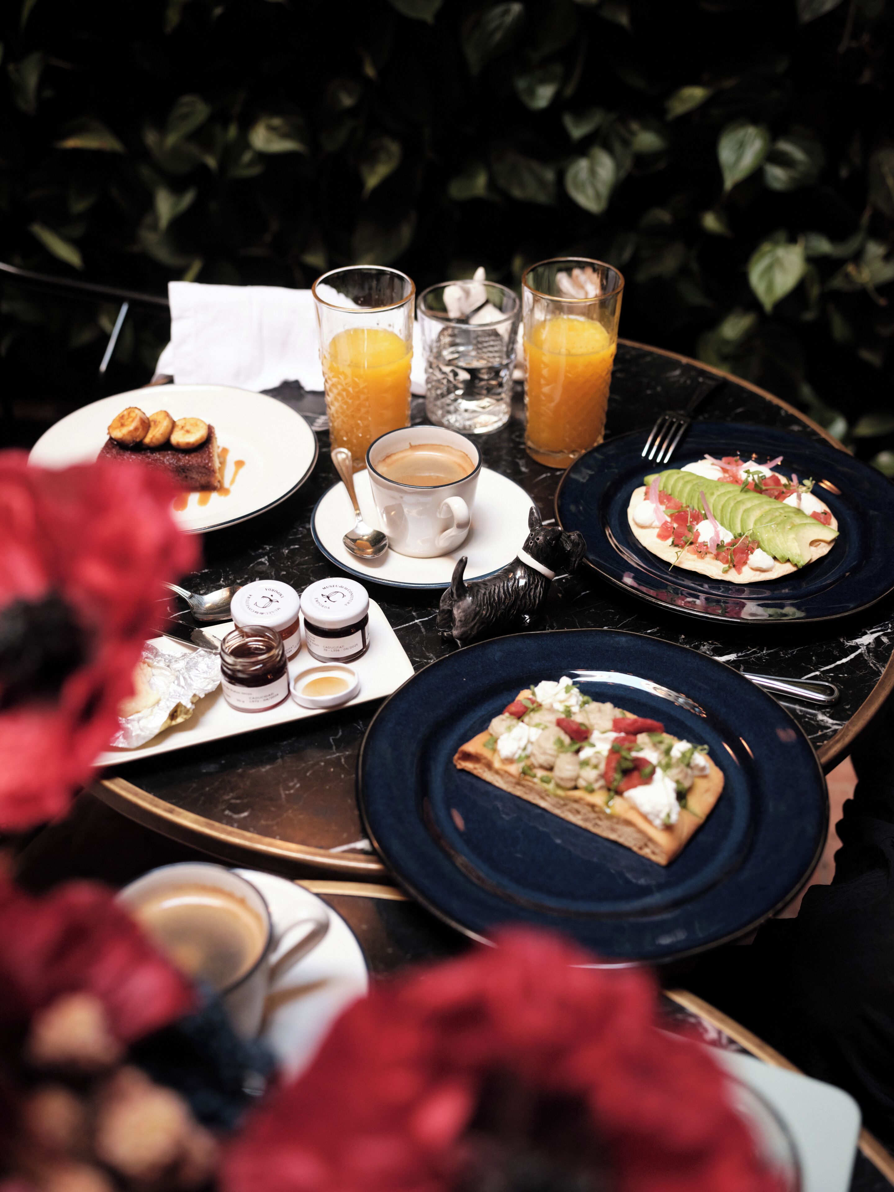 A table set with breakfast items including toast, a muffin, and a cup of coffee, with two glasses of orange juice.
