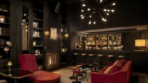 Un espace bar comprenant un comptoir, des tabourets et un canapé rouge.