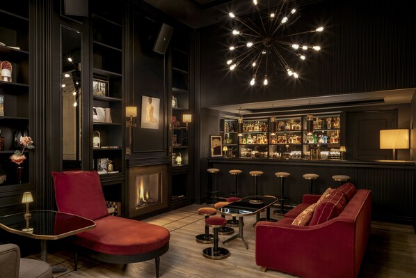 A bar area with a bar counter, stools, and a red sofa. - WITTMORE HOTEL - Adults Only (Barcelona)