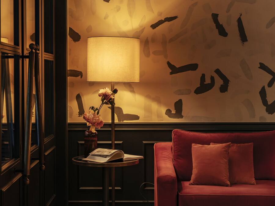 Una habitación con un sofá rojo, una lámpara y una pared con diseños abstractos.