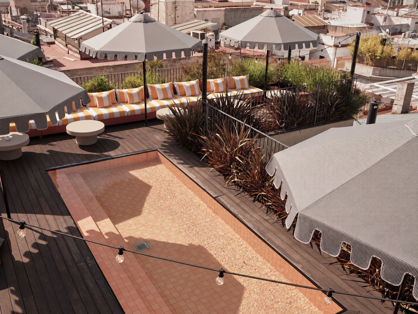 An outdoor seating area with a wooden deck, a lounge with striped cushions, and a covered section with chairs.