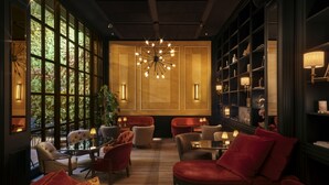 Un intérieur moderne avec une grande fenêtre, un lustre central et différents types d’agencements de sièges.
