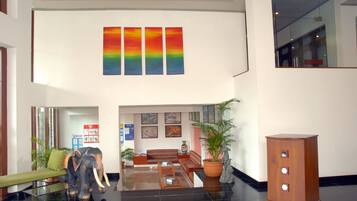 A lobby with a reception desk, a sofa, a coffee table, a potted plant, and a statue of an elephant.