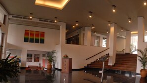 A spacious lobby with a staircase, potted plants, and artwork on the walls. - Camelot Beach Hotel (Negombo)