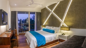 A modern hotel room with a large bed, a desk, and a view of the outdoors. - Camelot Beach Hotel (Negombo)