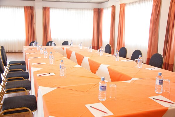 A conference room with a long table, chairs, water bottles, and documents. - Camelot Beach Hotel (Negombo)
