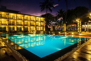 Un hotel con piscina, varios balcones y zonas de estar al aire libre.