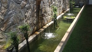 A stone wall with a water feature, including a small pond and a waterfall. - Camelot Beach Hotel (Negombo)