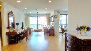 Un vaste salon doté d’un plancher en bois, un coin repas avec une table et des chaises, un canapé et un meuble décoratif.
