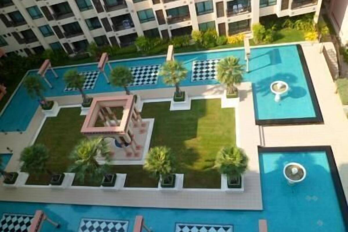 A rooftop pool area with multiple pools, palm trees, and a checkered lounge area.