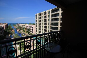 A view from a balcony overlooking a swimming pool and a hotel building with multiple floors and balconies. - Marrakesh Condo Residence by Hua hin property online (Hua Hin)
